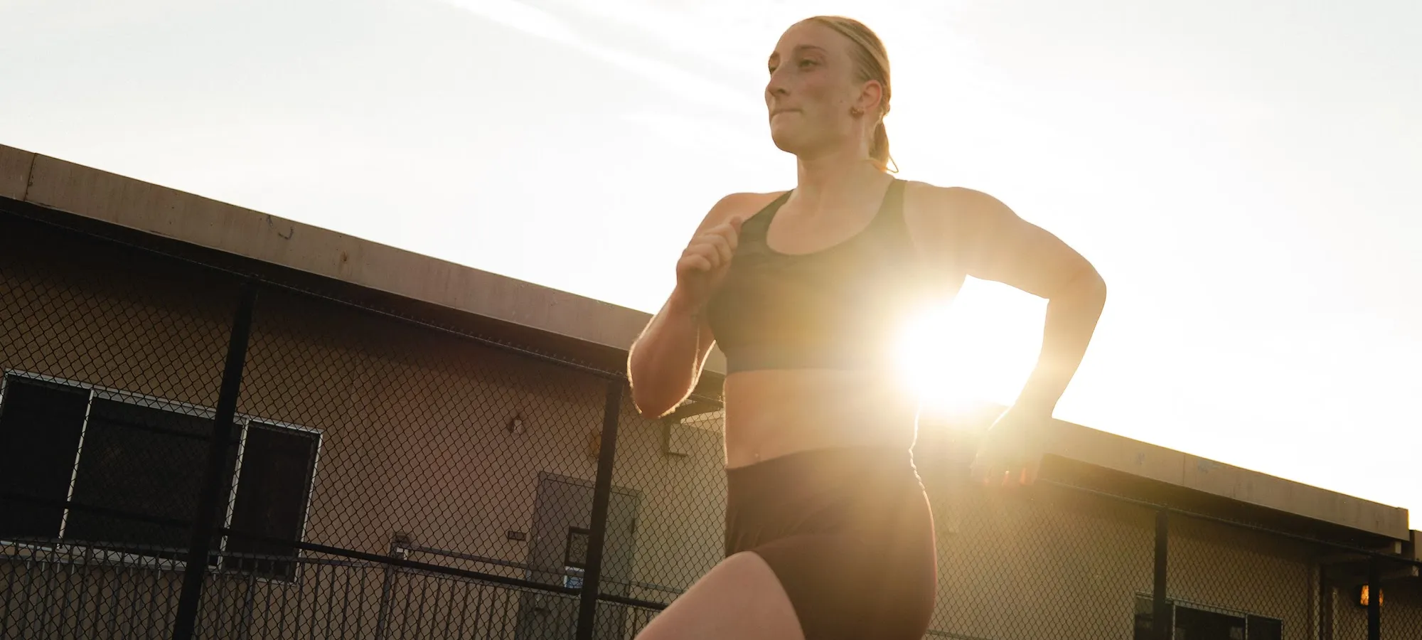 Runner sprinting through the sunset flare on the track